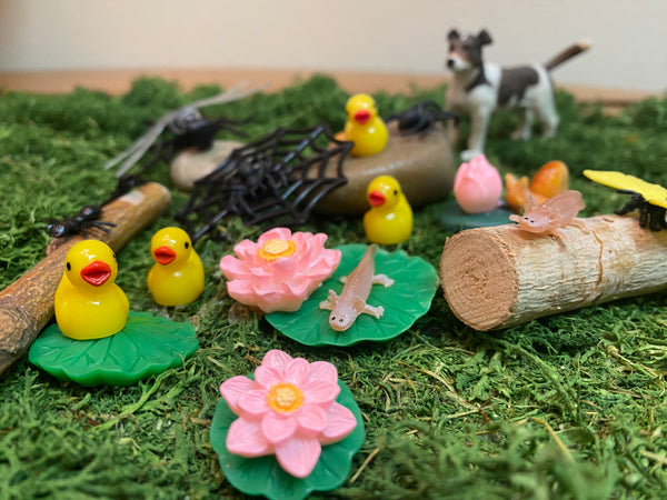 Miniature ducklings, axolotls, ants on a grassy background.  Jack Russell Terrier in the background.